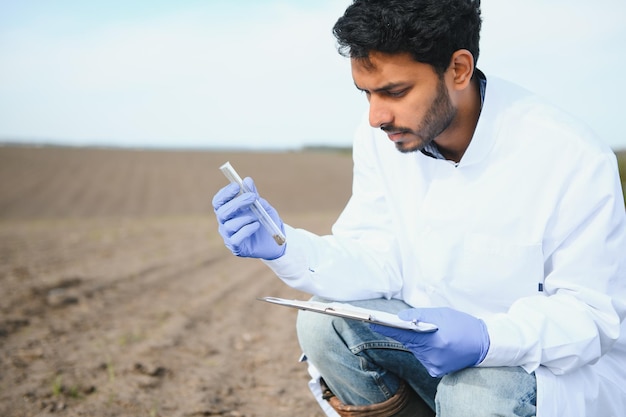 Soil Test Indian Agronomist putting soil with garden shovel in soil sample bag outdoor Environmental research