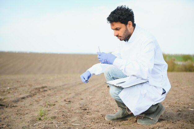 Soil Testing Indian Agronomy Specialist taking soil sample for fertility analysis Hands in gloves close up Environmental protection organic soil certification field work research