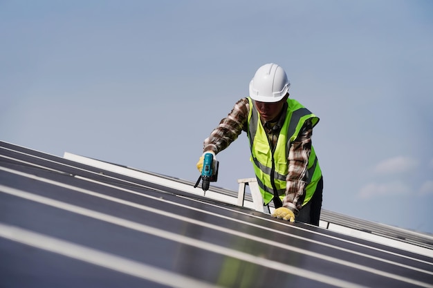 太陽電池技術エンジニアは、工場の屋根の再生可能エネルギーの概念における太陽電池の設置と太陽電池の修理を調査しています