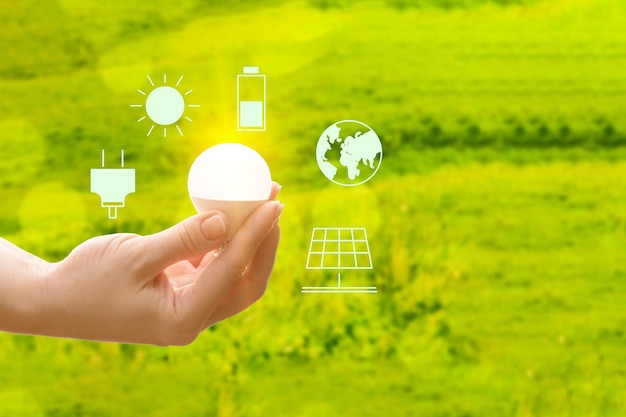 복사 공간이 있는 자연의 녹색 배경에 손에 들고 있는 태양 에너지 아이콘 재생 가능 에너지 표지판 생태 개념 환경 관리 램프