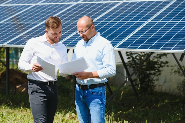 The solar farm(solar panel) with two engineers walk to check\
the operation of the system, alternative energy to conserve the\
world\'s energy, photovoltaic module idea for clean energy\
production