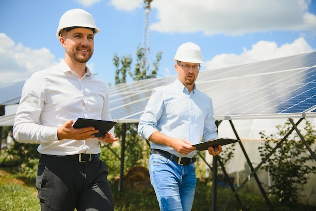 The solar farm(solar panel) with two engineers walk to check\
the operation of the system, alternative energy to conserve the\
world\'s energy, photovoltaic module idea for clean energy\
production