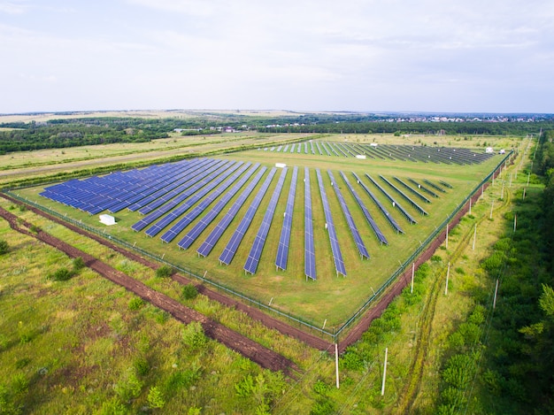 青い空と緑の芝生の上の太陽電池パネル。