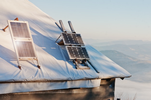 Solar panels on the roof of alone wood house on mountain.