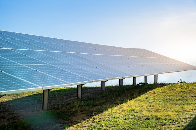 青い空と太陽のある緑の野原にあるソーラーパネルシステム 再生可能で持続可能なエネルギー