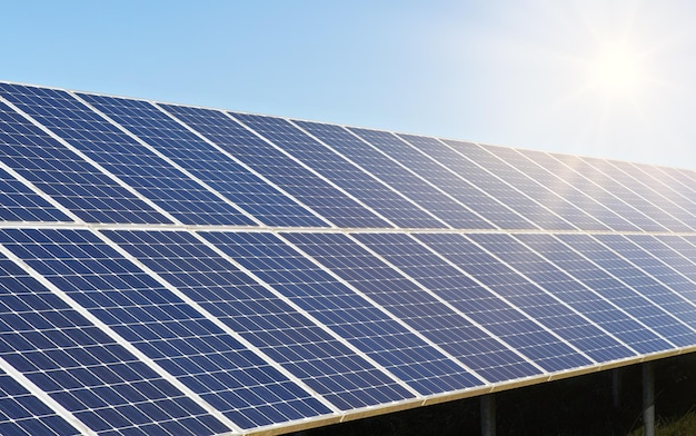 Solar photovoltaic panels, with clear sky and shinning sun above, closeup detail.