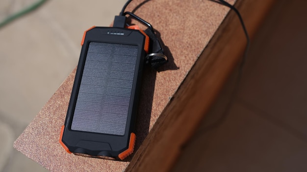 Solar power bank for charging mobile phone lying under rays of sun closeup