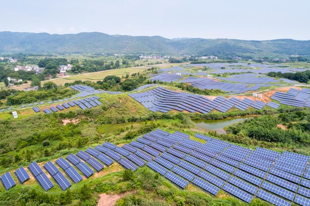 山岳地帯の再生可能エネルギーの丘の中腹の空中写真にある太陽光発電所