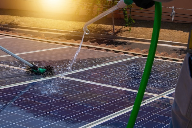 Solar worker cleaning photovoltaic panels with brush and water. Photovoltaic cleaning.