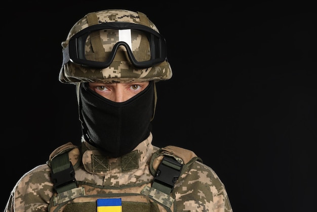 Soldaat in Oekraïens militair uniform tactische bril en bivakmuts op zwarte achtergrond Ruimte voor tekst