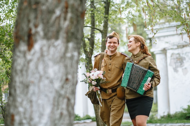 Soldaat loopt door het steegje en omhelst een militaire vrouw die een accordeon speelt