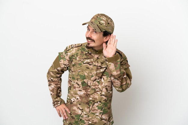 Foto soldaat man geïsoleerd op een witte achtergrond luisteren naar iets door hand op het oor te leggen