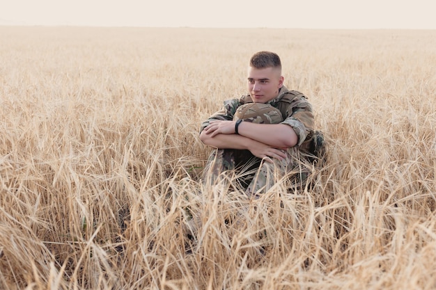 Soldaat man staande tegen een veld. Portret van gelukkige militaire soldaat in bootcamp. US Army soldaat in de missie. oorlog en emotioneel concept.