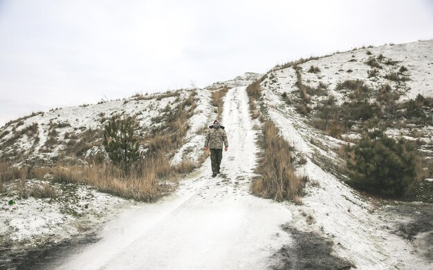 Soldaat staat in het camouflage-uniform en de geruite keffiyeh shemagh bandana. De mens is buiten op de verlaten verlaten plek.