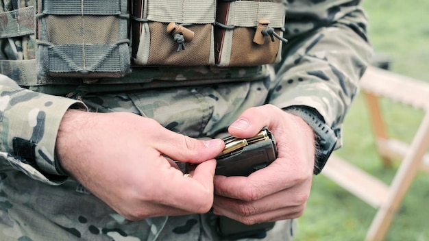 Soldaten laden munitie in een magazijn close-up van een soldaat in camouflage uniform laden