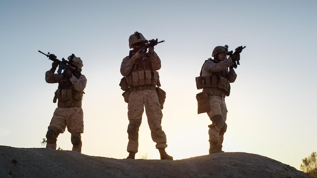 Soldaten staan op een heuvel voor een zonsondergang