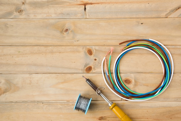 Фото Паяльник и паяльная проволока с цветным кабелем на деревянной поверхности
