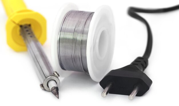 Soldering iron with spool of solder over white background