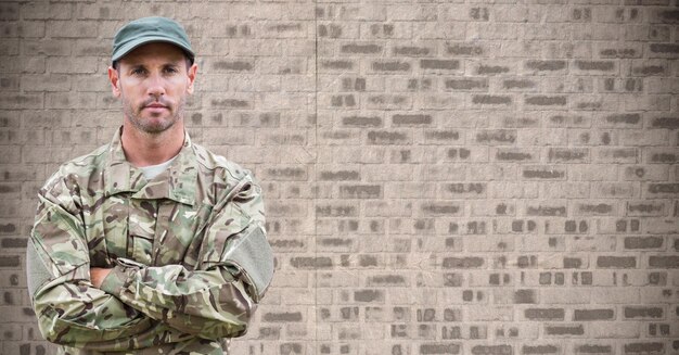 Soldier arms folded against brown brick wall