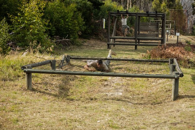 Soldier crawling under the net during obstacle course