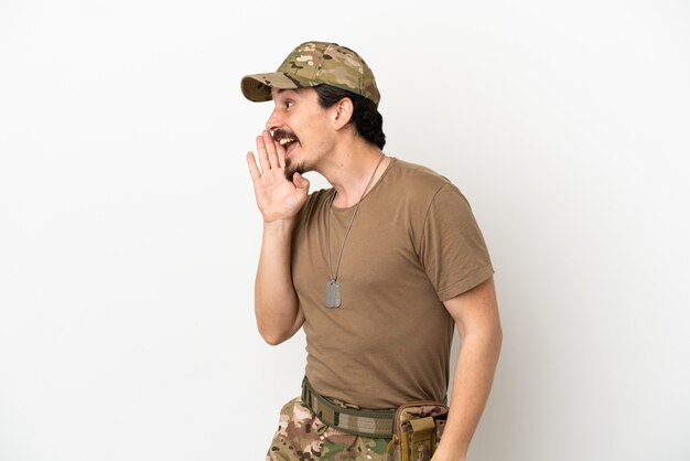 Soldier man isolated on white background shouting with mouth wide open to the lateral