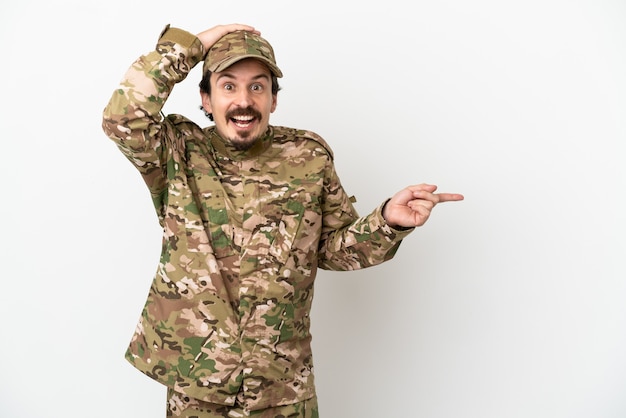 Soldier man isolated on white background surprised and pointing finger to the side