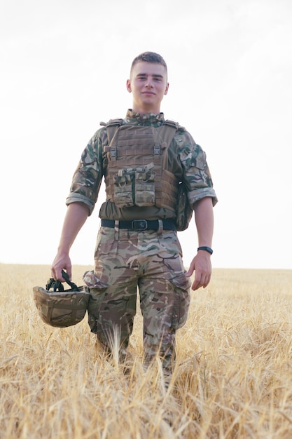 Soldier man standing against a field. Portrait of happy military soldier in boot camp. US Army soldier in the Mission. war and emotional concept.