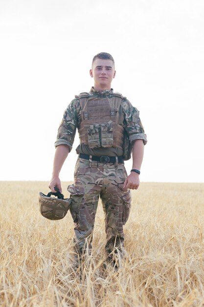 Soldier man standing against a field. Portrait of happy military soldier in boot camp. US Army soldier in the Mission. war and emotional concept.