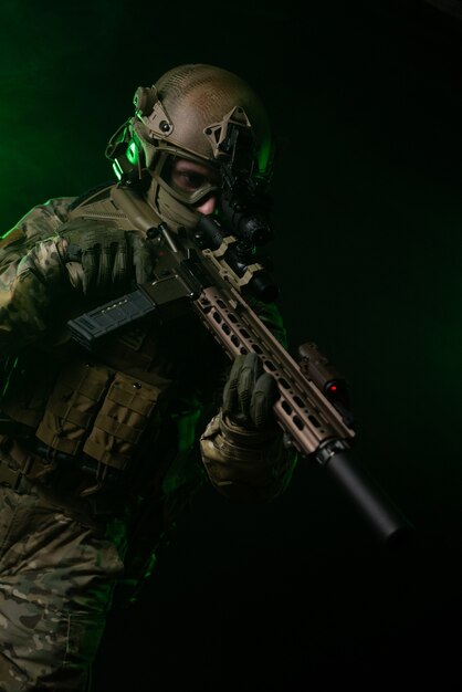 The soldier in military clothing with a night vision device and on a dark background