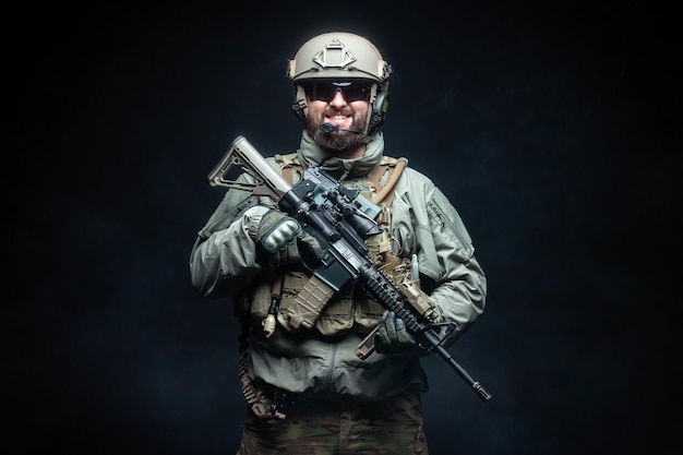 Soldier in military equipment with a rifle smiles at night a commando in uniform