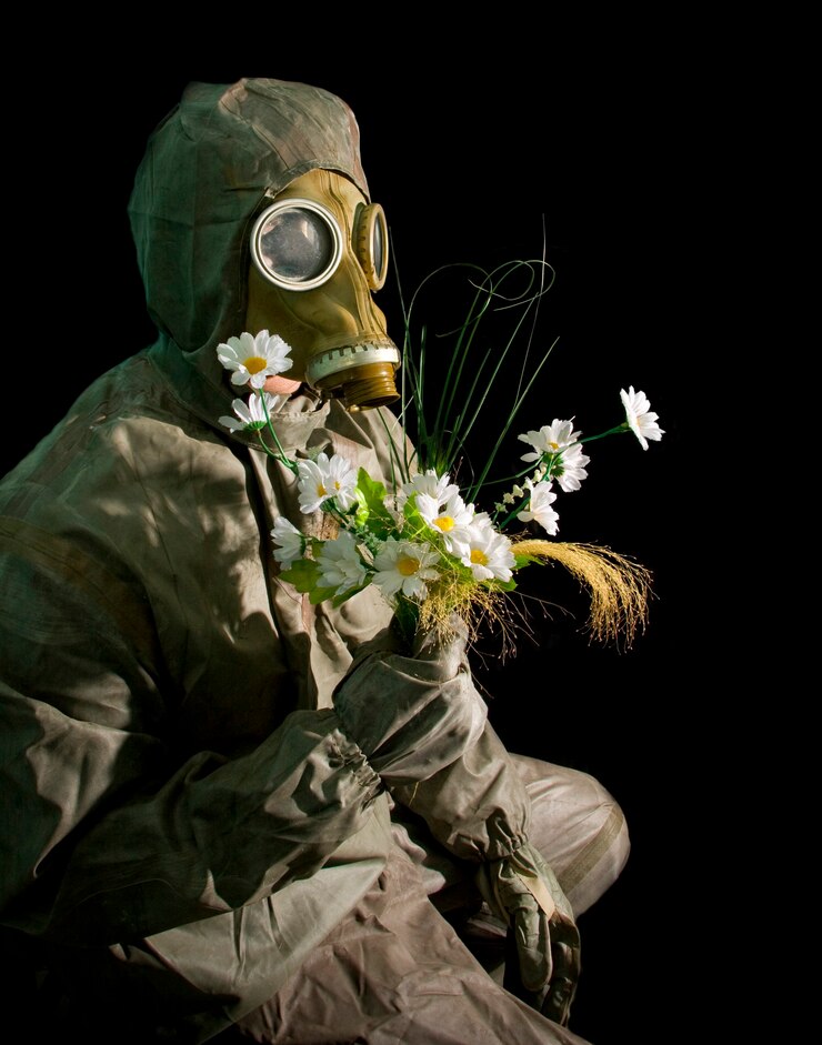 Photo soldier in protective gear and gas mask with flowers on black