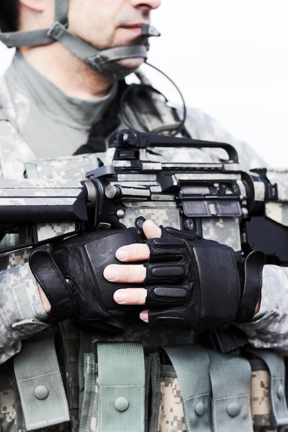 Photo soldier ready at rest. closeup cropped shot of the midriff of a soldier holding his gun against his chest.