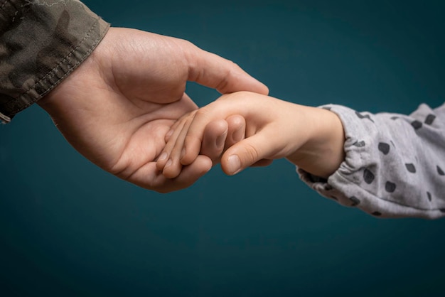 A soldier's hand holds a child's hand in closeup Father is a military man A soldier and a child