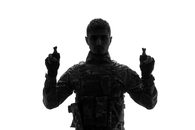 Солдатский силуэт серьезный красивый сильный крепкий армейский солдат в униформе скрещивает пальцы