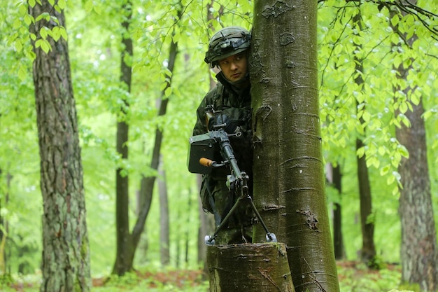 A soldier behind a tree is behind a tree