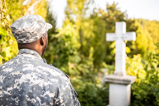 Soldier in uniform standing still at cemetery in honor to fallen war heroes