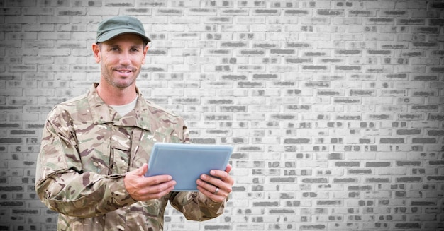 Soldier with tablet against white brick wall