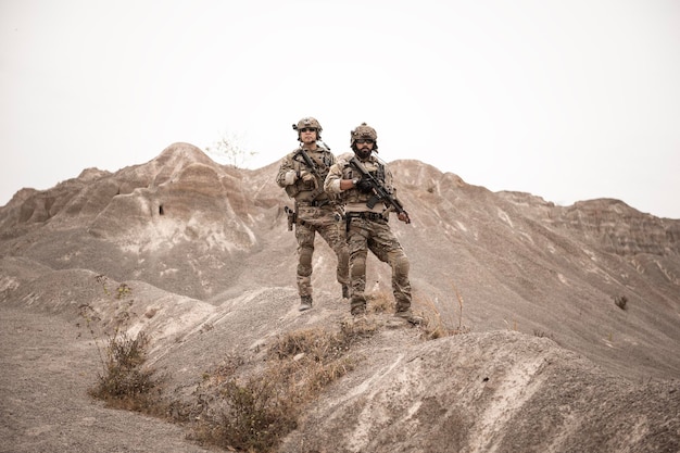 Soldiers in camouflage uniforms aiming with their rifles ready to fire during military operation