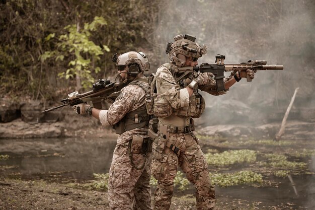 Soldiers in camouflage uniforms aiming with their rifles