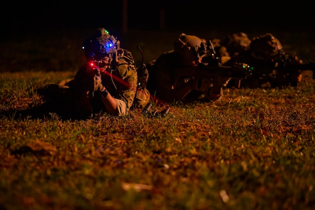 Soldiers in camouflage uniforms aiming with their riflesduring Military Operation at night soldiers