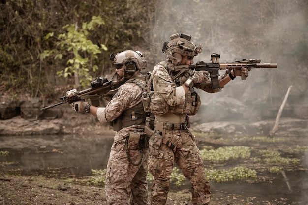 写真 カモフラージュのユニフォームを着た兵士がライフルを狙っている