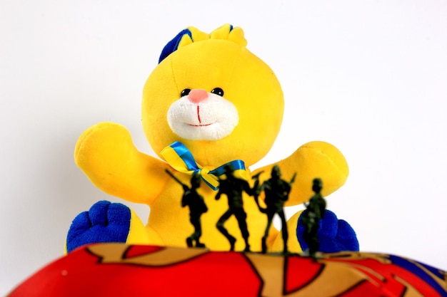 Soldiers silhouettes on The toy bunny in the national colors of Ukraine on background