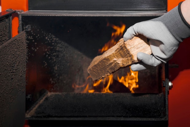 Solid Fuel Boiler and Heating House concept. Man Loading Firewood on Modern Solid Fuel Boiler.