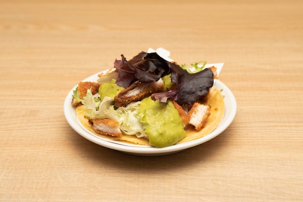 Solitaire mariachi taco met guacamole crème gebakken kip in beslag en eiken sla op houten tafel