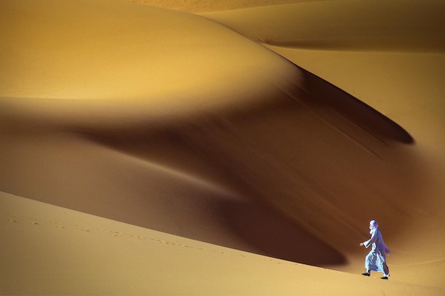 Photo solitary man walking through sahara desert