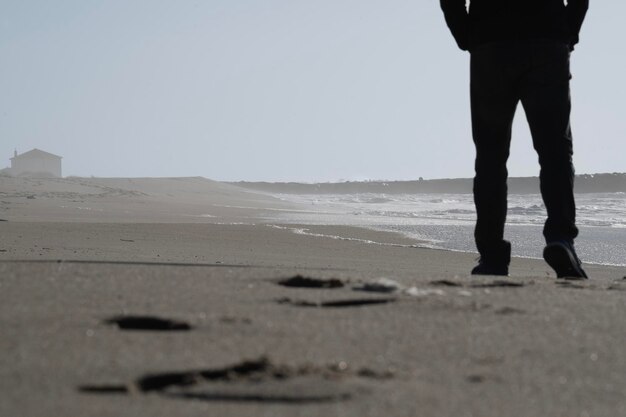 Photo solitude by the sea low angle view silhouette of boy walking along the beach