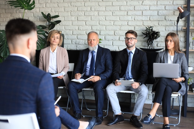 Sollicitatiegesprek met de werkgever, zakenman luistert naar antwoorden van kandidaten.