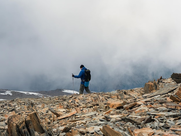 一人登山活動男は霧の石の丘の頂上に登る困難な状況にある人々山の霧の日山の頂上に登るのは難しい