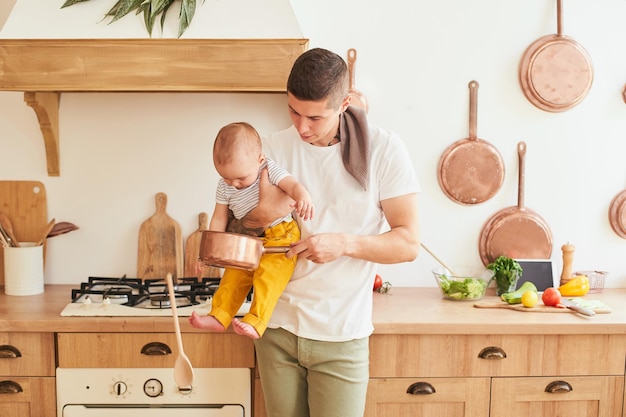 Photo solo dad with his son in his arms in the kitchen of the house