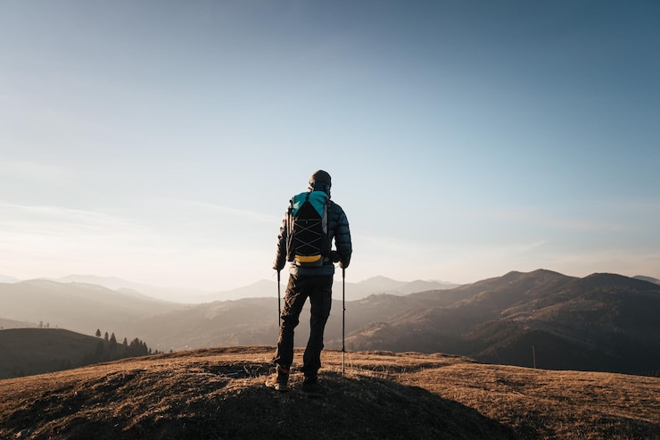 Photo solo hiker on mountain at sunrise with trekking poles